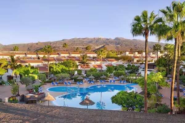 Wyndham Residences resort with swimming pool, palm trees, and mountain backdrop